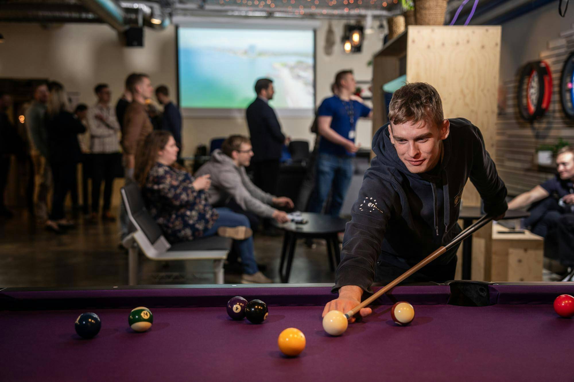 Syndis employees enjoying a game of billiards at the Reykjavik office during a social event, showcasing the company’s friendly and relaxed workplace culture.