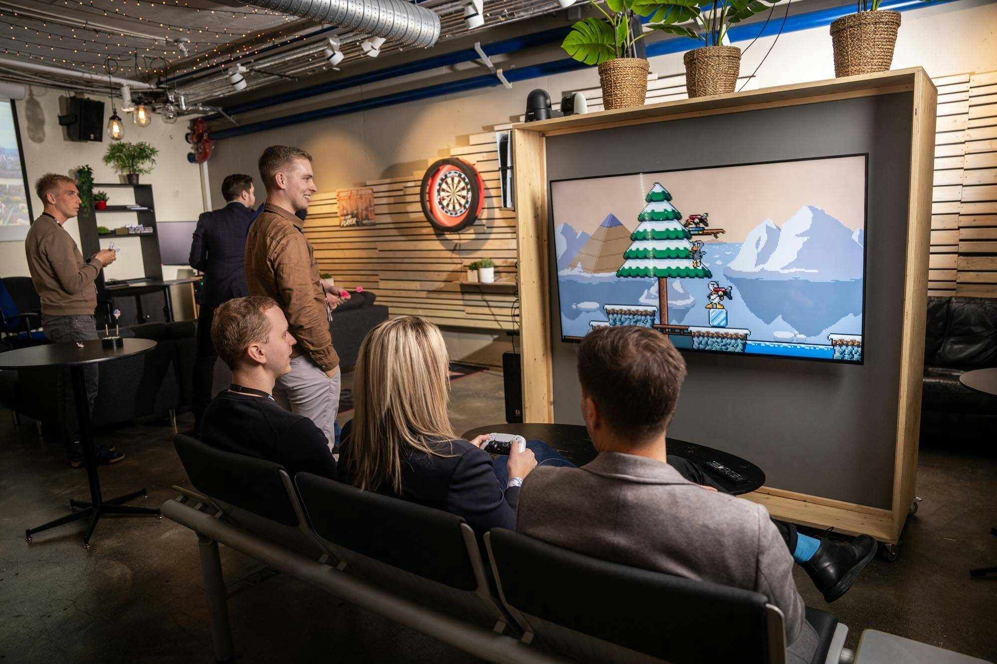 Syndis employees relaxing together, playing video games and darts in the Reykjavik office, highlighting the company’s fun and collaborative culture.